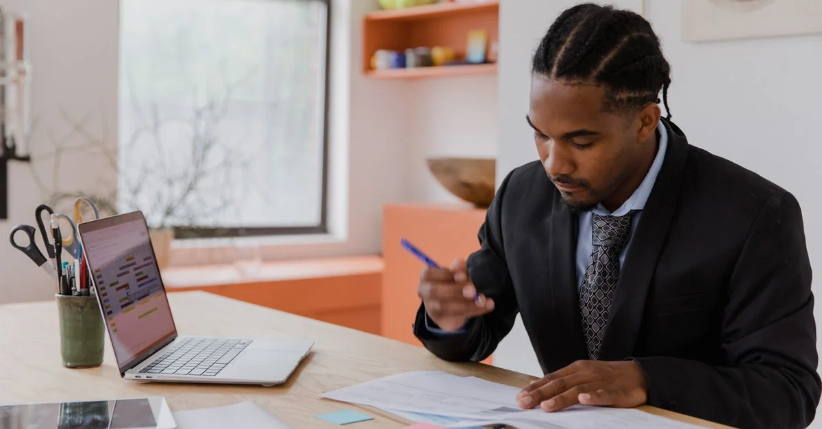 Un homme d'affaires professionnel travaillant à son bureau, examinant des documents dans un environnement de bureau moderne.