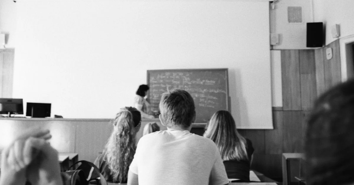 Une photo en noir et blanc d'étudiants et d'un enseignant dans une salle de classe, concentrés sur l'apprentissage.
