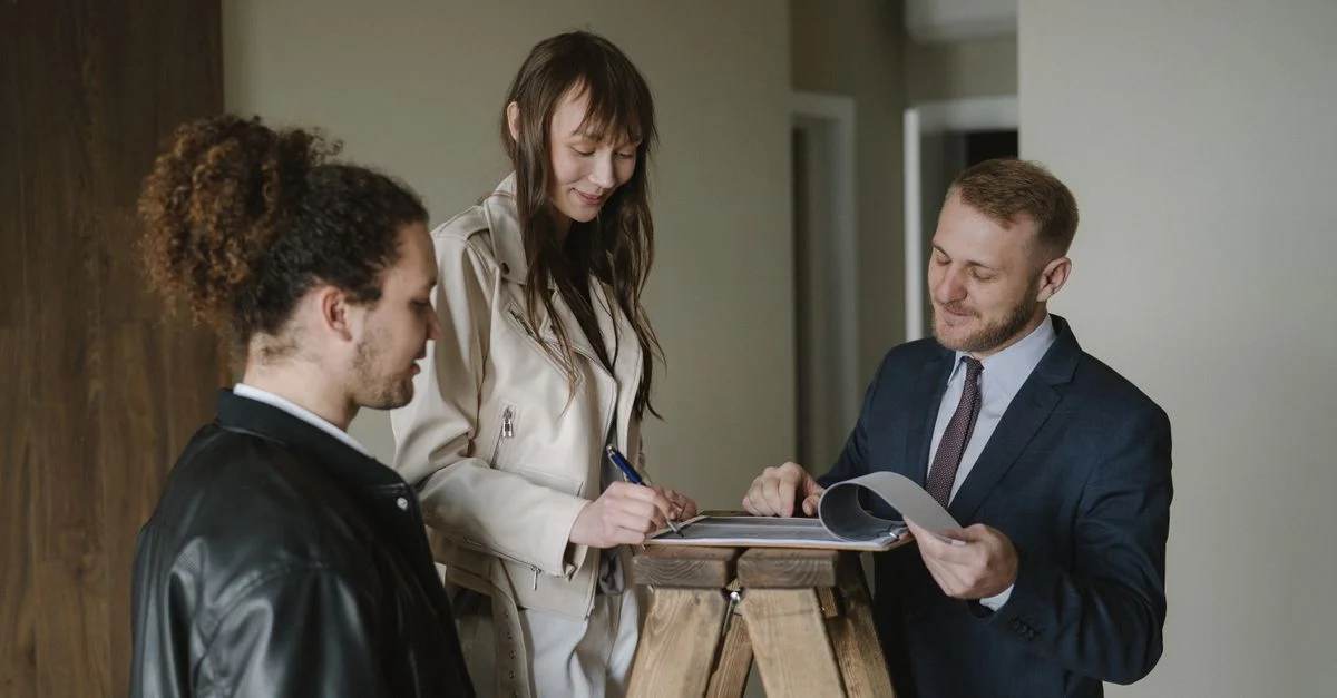 Un couple signant des documents immobiliers avec un agent dans un nouvel appartement.