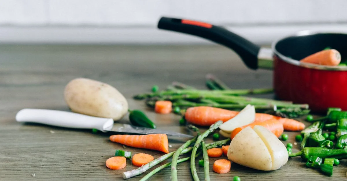 Une sélection de légumes frais avec un couteau sur une surface en bois, parfaits pour la cuisine saine et la préparation des aliments.