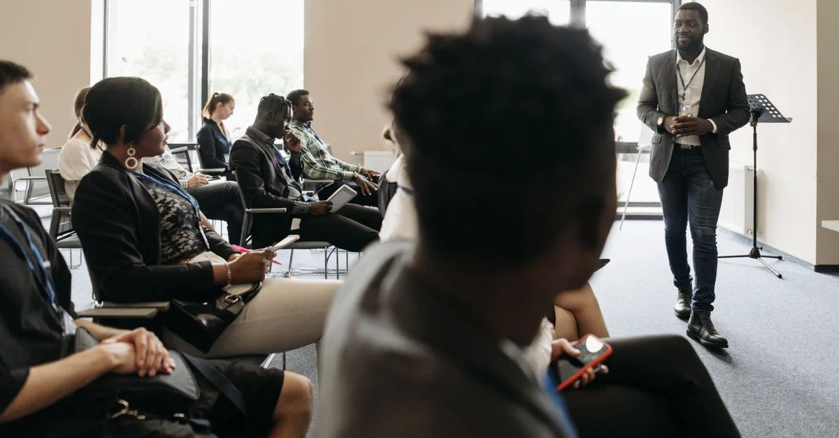 Des professionnels divers engagés dans une présentation interactive dans une salle de conférence moderne.
