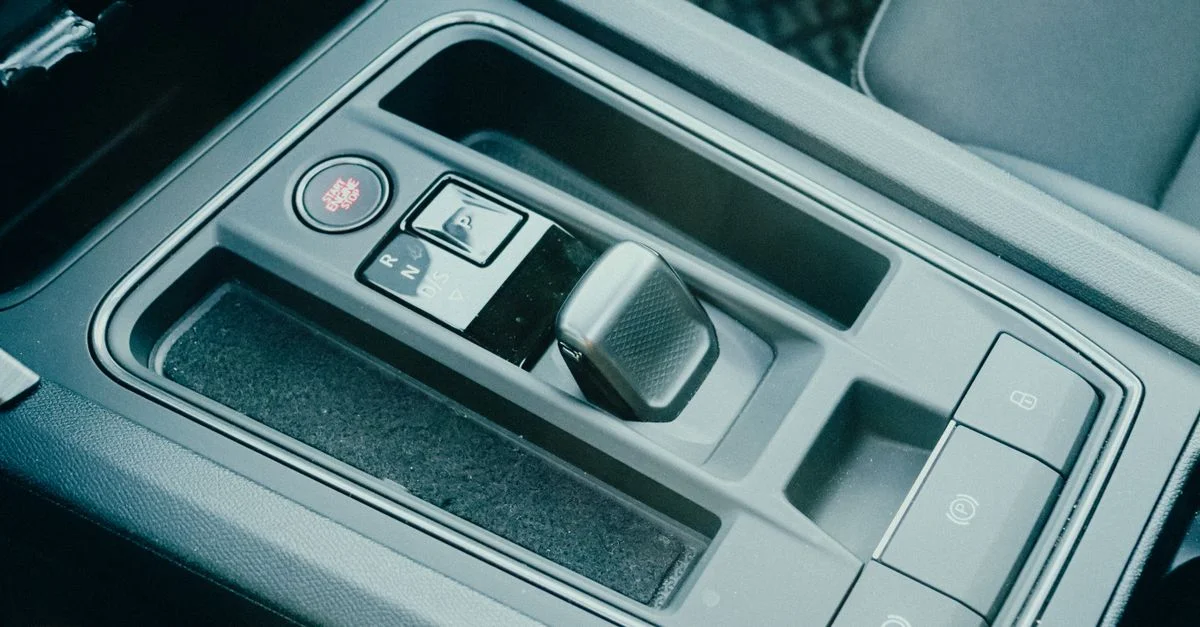 Gros plan du pommeau de levier de vitesse d'une voiture moderne dans un décor intérieur, mettant en valeur une technologie automobile avancée.
