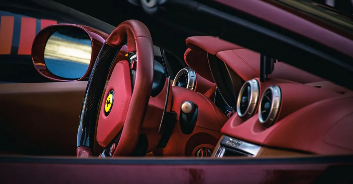 Gros plan de l'intérieur d'une voiture de sport de luxe présentant des sièges et un volant en cuir rouge.