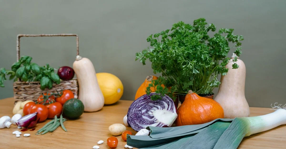 Une variété assortie de légumes frais comprenant des courges, des tomates et des légumes verts sur une table en bois.