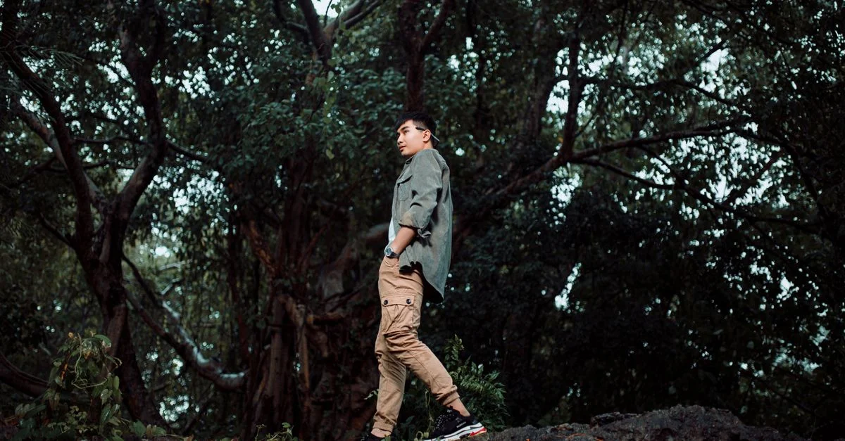 Homme debout dans un cadre forestier luxuriant, embrassant la nature sauvage lors d'une randonnée tranquille.